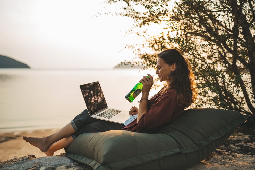 Woman sitting with laptop on the summer beach Working Remotely in Thailand 2022