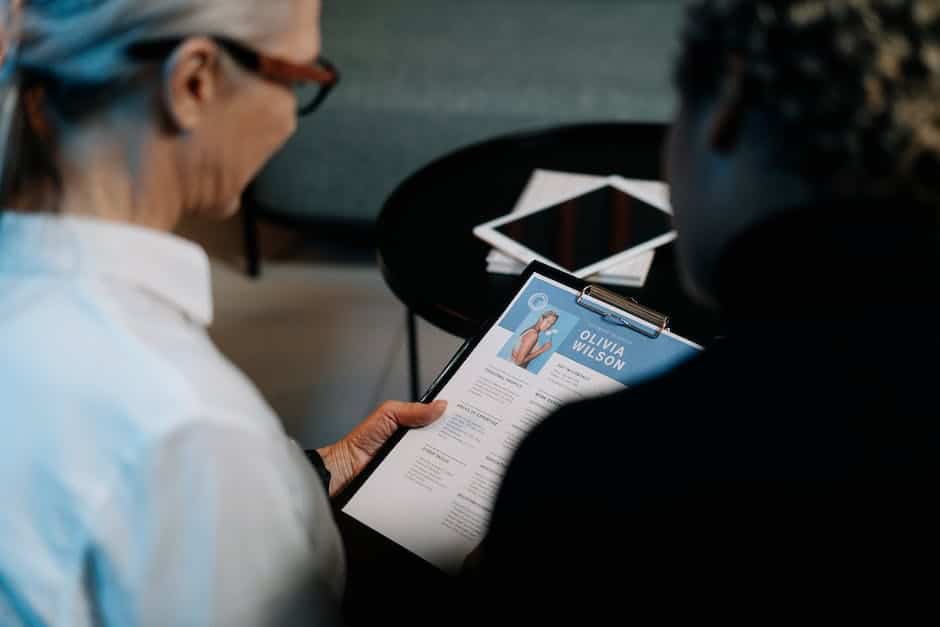 A person holding a resume with a magnifying glass, symbolizing the need for attention to detail in perfecting a job application.